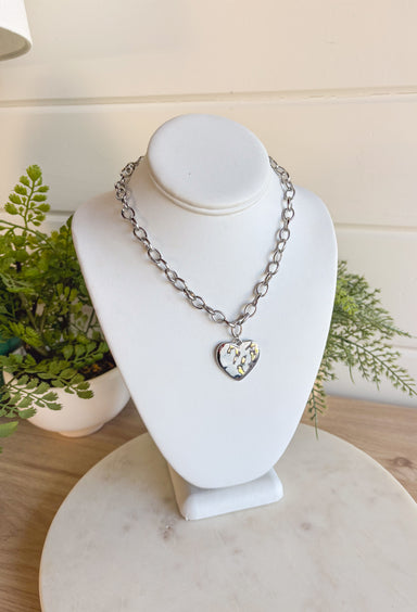 Simple, stylish, and oh-so versatile—this silver chain necklace is the perfect finishing touch for any look. Designed with a textured heart charm, it adds just the right amount of detail and personality without overpowering your outfit. With its adjustable extender, you can wear it closer to the neckline for layering or a little longer on its own. A timeless piece you’ll keep reaching for, no matter the occasion.