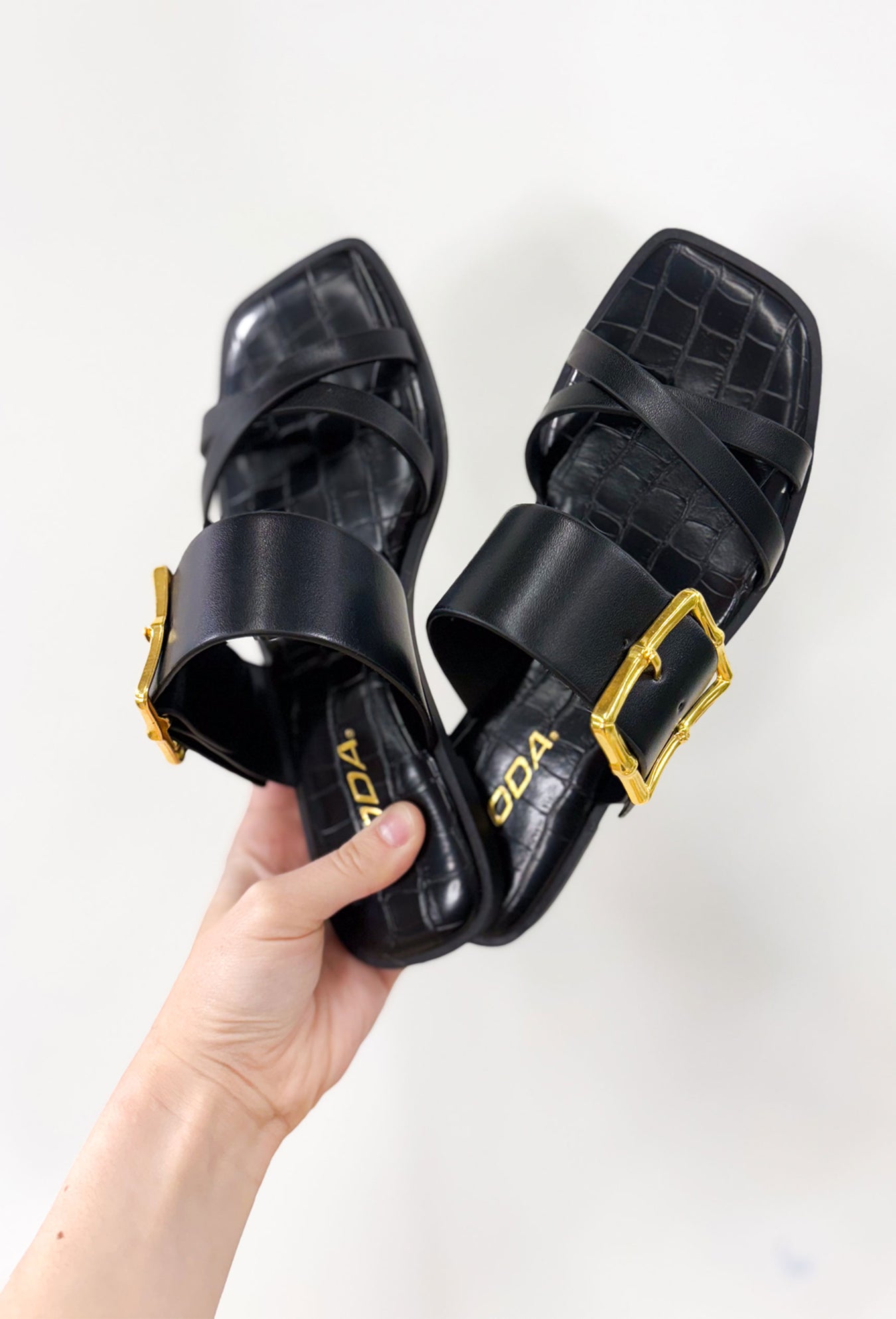 Flaxen Sandals in Black, flat sole faux leather strapped sandals with two small straps over the toes and one big strap over the top of the foot with a gold bamboo buckle