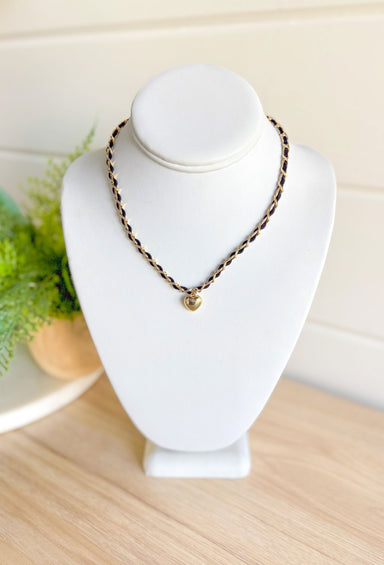 Heart On The Line Necklace, black string intertwined in a gold chain with a gold heart charm in the center