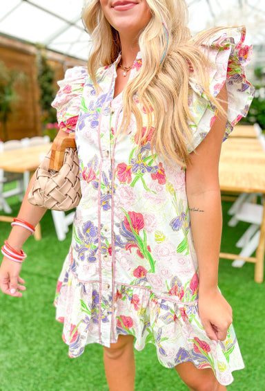 Sound Of Spring Floral Dress, ruffle sleeve button down dress with tiering at the bottom, v-neck, and floral print. White base with purple, light pink, rose, fuchsia, lime, sage, spring green, and pale yellow floral pattern