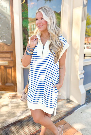 What Do You Mean Dress in Cream & Blue, quarter zip collared dress with white hemming on the sleeves, neck, and bottom of the dress. Blue and white horizontal stripes across the dress