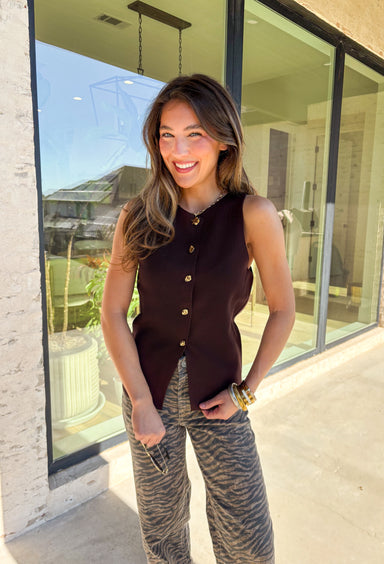 Classic meets modern in this sleeveless brown sweater by Iris. The button-down design is elevated with gold hammered buttons that add a chic, statement touch. Crafted in a soft knit with a lightweight feel, it’s perfect for layering under jackets or wearing solo on warmer days. A versatile piece that easily transitions from casual outings to dressier occasions.