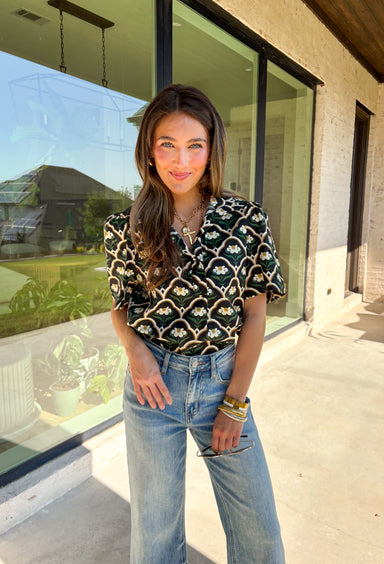 Polished with a hint of romance, this black puff shoulder top is the perfect way to bring fall florals into your wardrobe. The seasonal print in rich, neutral tones pairs beautifully with the structured puff sleeves and high neckline, while a pearl-accent single button closure at the front adds an elegant finishing touch. Crafted with a soft cotton blend and just the right amount of stretch, it’s comfortable enough for all-day wear yet dressy enough for special occasions.