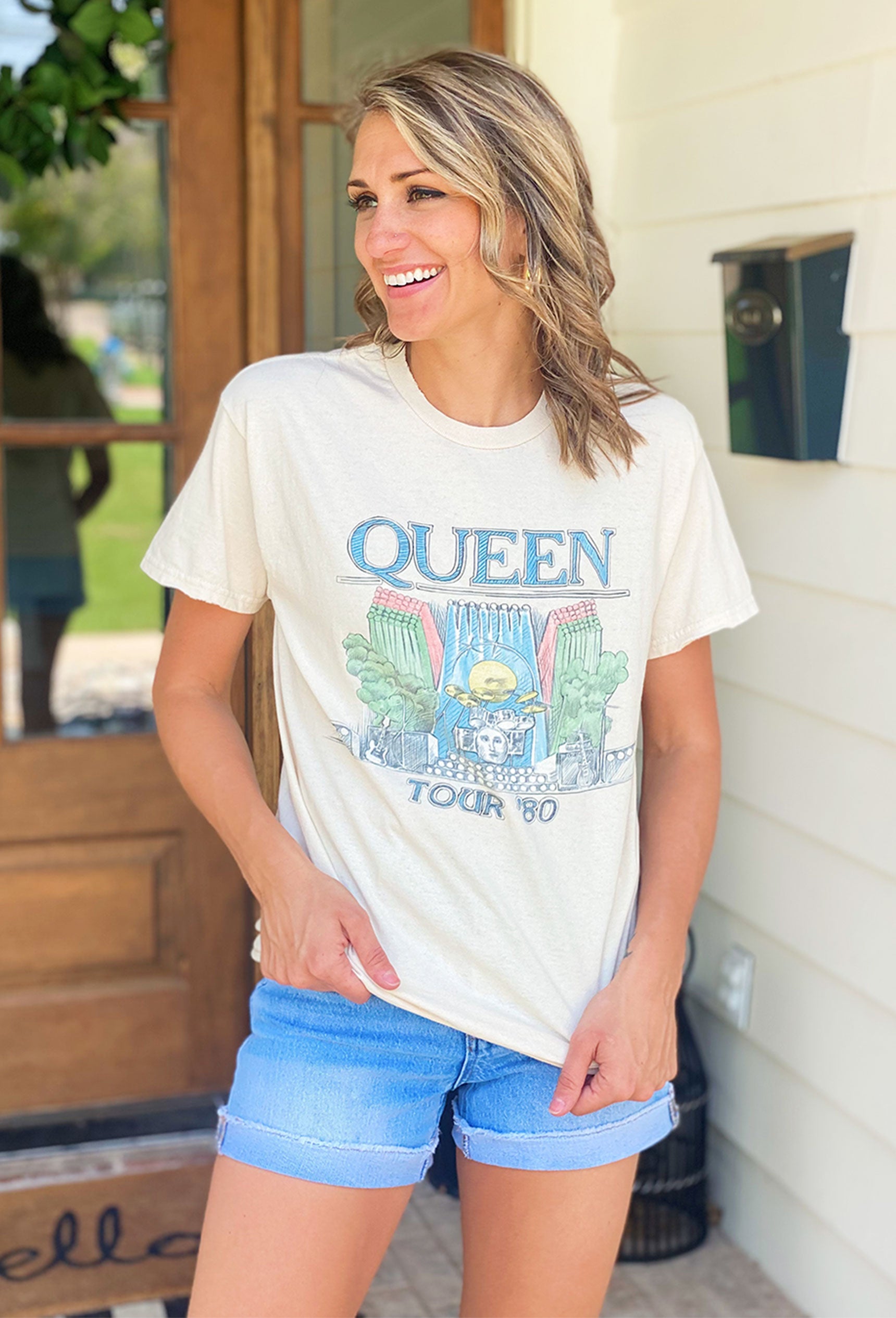 Queen Graphic Tee, neutral tee features the iconic "Queen Tour '80" logo and an on stage graphic