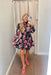 Sweetest Wish Floral Dress, black longsleeve dress with high neck that has cinching and ruffle hem along with cinched wrists with ruffle hem. 2 tiers and red, gold, purple, and green floral pattern