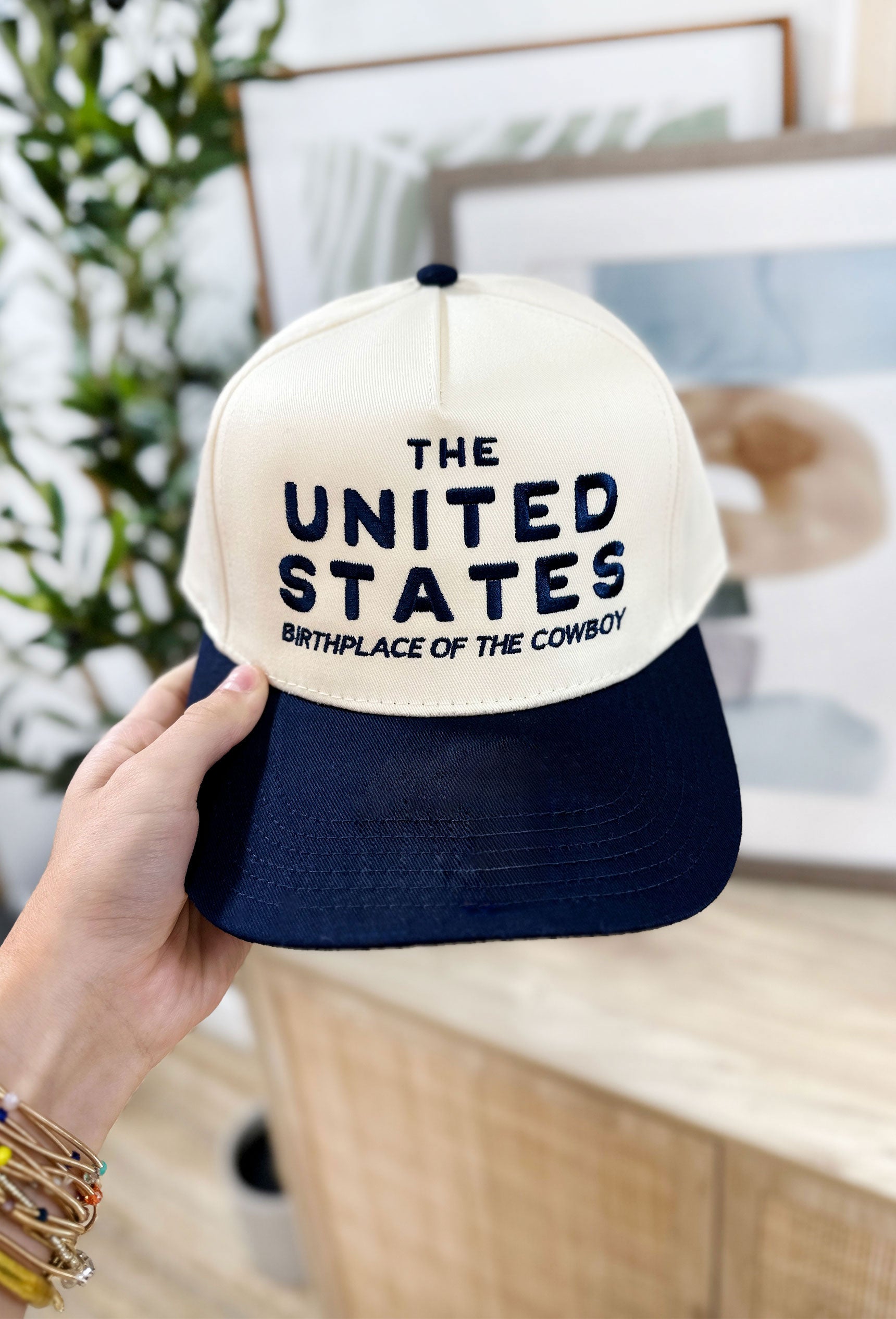 Friday + Saturday: Birthplace Of The Cowboy Trucker Hat, Ball Cap in off white and navy embroidered with "The United States birthplace of the cowboy"