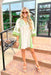 All For You Dress, beige base with muted green detailing down the sides and around the bottom of the sleeves, embroidered leaf and flower details around the chest and on the sleeves in muted green, kelly green and yellow 