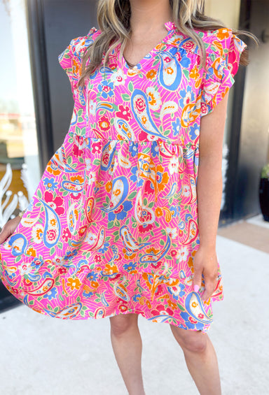 Flower Bomb Dress, paisley floral print short sleeve dress. Ruffle detailing on the sleeves and neckline, in the colors pink, periwinkle, yellow, orange, red, green, and cream 
