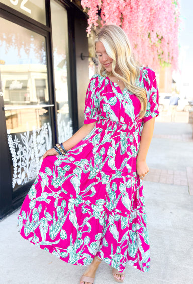 Garden Strolls Midi Dress, hot pink short sleeve midi dress white and green tulip design on the whole dress, cinching on the waist, v-neck line, and tiering on the bottom half of the dress
