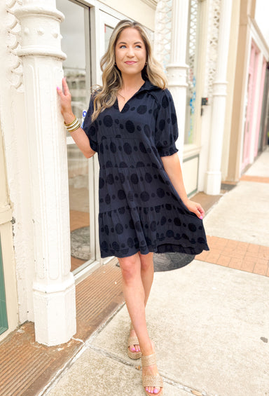 Hope You Know Dress in Navy, gauze dull navy short sleeve v-neck dress with a collar, textured polkadots all over the dress, tiering, raw bottom hem, cinching at the bottom of the sleeves