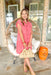 In The Morning Dress in Coral, short sleeve button up dress with two front pockets, buttons are brown and there is tiering down the dress