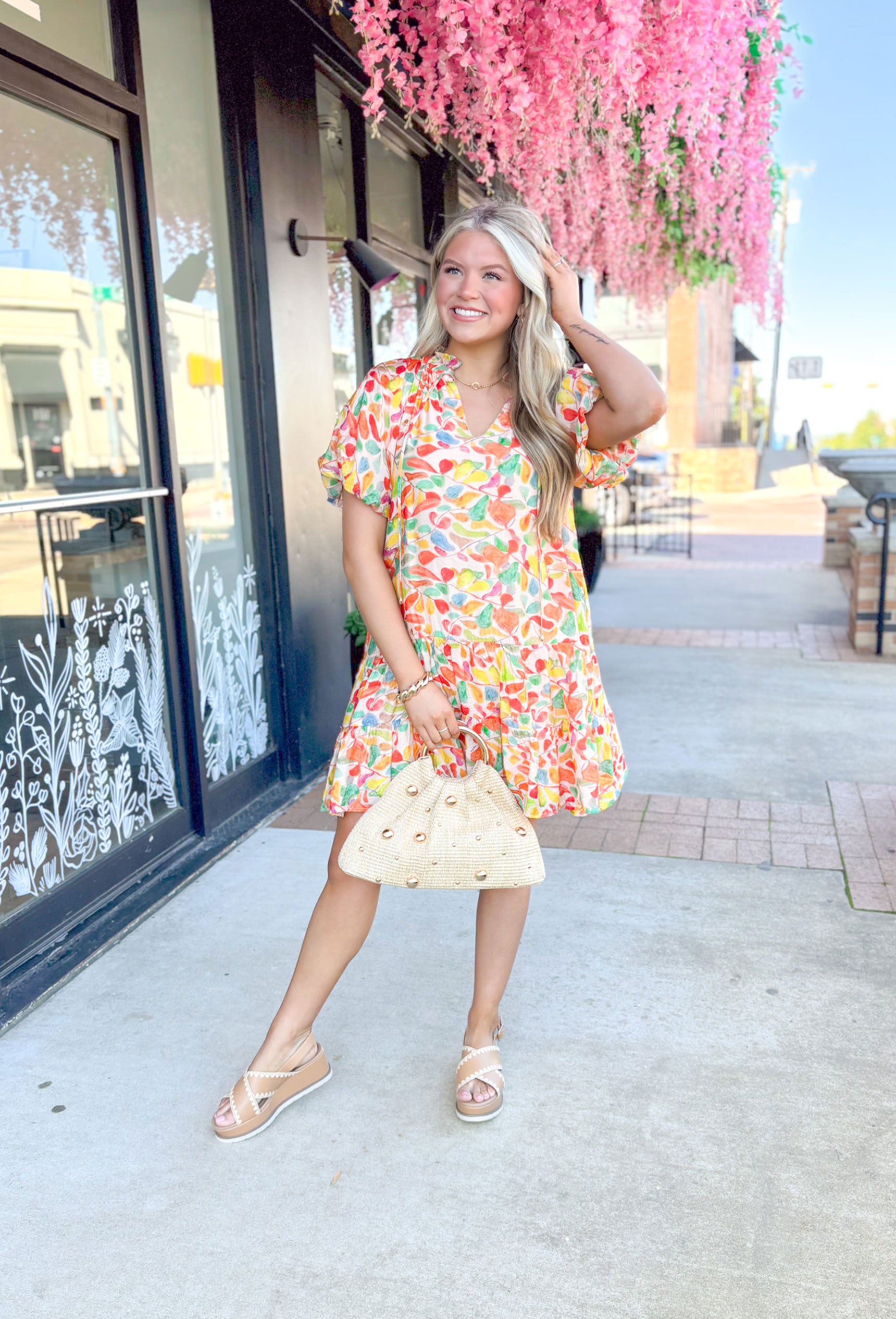 Paradise Awaits Dress, short puff sleeve dress with soft v-neck, ruffling around the neck, string details on the neck, abstract print in the colors cream, orange, yellow, red, and green