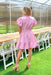 Park Avenue Dress in Pink, short puff sleeve dress with ruffles on the neck, n-neck line, double line cinching on the waist, pockets, and on layer of tiering at the bottom of the dress 