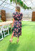 Social And Chic Floral Midi Dress, black high neck short sleeve midi dress with a blousy top and cinching on the top of the shoulders to pull the sleeve up. Floral pattern on the whole dress in the colors light pink, warm pink and green