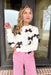 When In Paris Sweater, white knit sweater with black bows across the sleeves and chest
