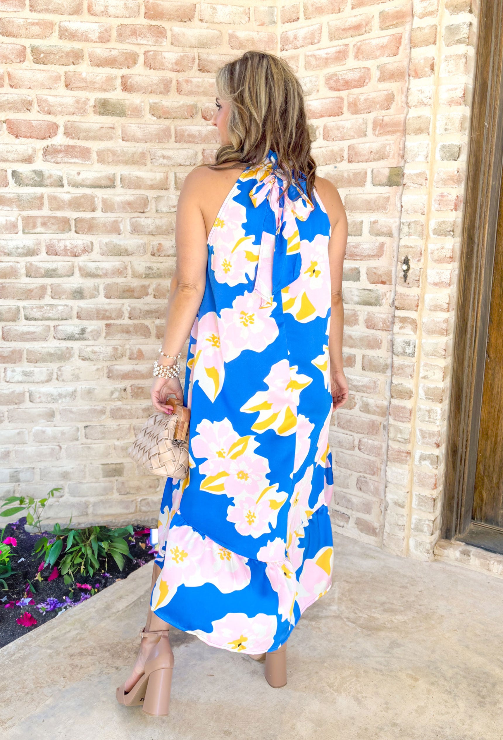 When You're Mine Dress, cobalt sleeveless high neck dress with ruffling on the neck. Floral pattern across the dress in light pink, white, and yellow with tier detail on the bottom of the dress