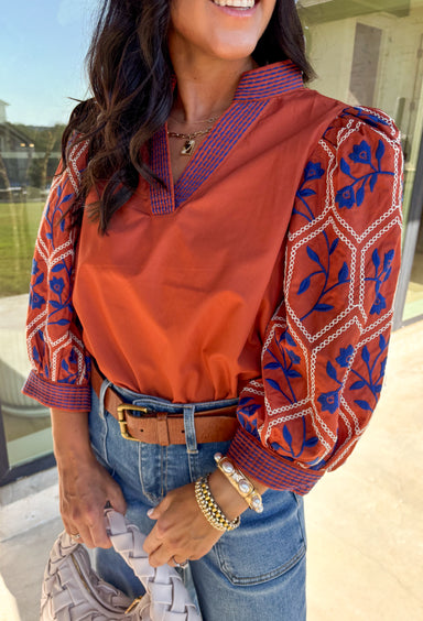 Rich and warm for the season, this rust top is beautifully detailed with a royal blue and cream floral embroidery that instantly stands out. The ¾ sleeves make it perfect for transitioning weather, while the embroidered stitch–embellished band adds an artisanal, elevated touch. Crafted from a soft, lightweight blend, it’s comfortable enough for all-day wear and versatile enough for pairing with denim, skirts, or trousers for a polished fall look.