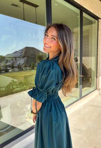 A statement piece with a touch of whimsy, this teal midi dress is designed to turn heads. Short puff sleeves and a flattering stitch-accent v-neckline pair beautifully with a defined waistband, while the embroidered skirt hem adds that extra bit of charm. The zipper front closure offers a modern twist, and the smocked waistband at the back ensures all-day comfort. This is perfect for any fall occasion!