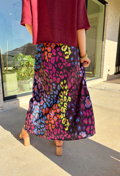 Bold and playful with a sleek twist, this satin maxi skirt is ready to steal the spotlight. The black background makes the vibrant leopard print—lime green, orange, pink, purple, and blue—pop beautifully, giving you a statement piece that still feels versatile. The elastic waistband keeps it comfortable and easy to wear, while the flowing maxi length adds a touch of drama. Perfect for dressing up with heels or styling casually with a tucked-in sweater and sneakers, this skirt brings a punch of personality t