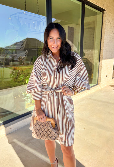 Classic stripes get a fresh fall update in this brown and cream shirt dress. Designed with a button-front closure and ¾ sleeves finished with button cuffs, it has a polished yet relaxed vibe. A self-tie belt cinches the waist for a flattering fit, while side pockets and a full lining add comfort and practicality. Lightweight and versatile, this is a dress you can easily style for workdays, weekends, or seasonal gatherings.