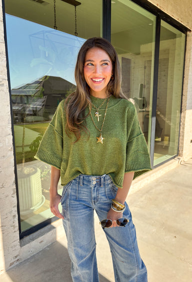 Cozy with a modern edge, this olive green sweater is an easy go-to for cooler days. Designed with a mock neck and cropped length, it’s finished with exposed seam details that add a casual, laid-back vibe. Ribbed cuffs and hem bring structure to the soft knit, while the lightweight blend makes it perfect for layering. A versatile piece that pairs effortlessly with denim, skirts, or wide-leg pants for fall.
