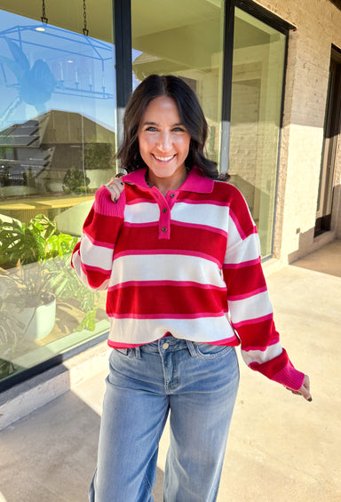 This striped sweater is giving retro prep meets pumpkin spice—and we’re here for it. With bold red, playful pink, and classic white stripes, it brings a cheerful twist to gloomy fall days. The collared neckline and front button details add a polished touch that feels just right for layering over your favorite jeans or corduroy skirt. Made from soft, cozy acrylic, it’s a lightweight piece that still keeps you warm on crisp autumn mornings. Whether you’re headed to the office or a cider-sipping weekend, this 