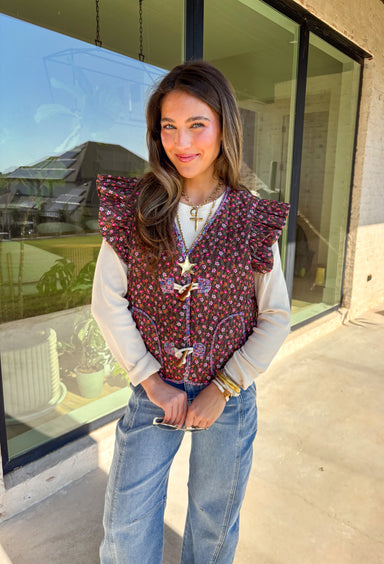 This charming quilted vest is giving all the cozy fall vibes with a pop of cheerful color. The brown base is covered in a dainty floral print in soft shades of pink, orange, and green—perfect for layering over your favorite long sleeve tops. Ruffle sleeves and oversized button closures add just the right amount of whimsy!