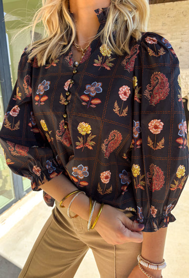 A statement piece for the season, this black top by Entro brings together rich autumn tones and timeless details. Featuring a mix of floral and paisley prints, it’s designed with ¾ puff sleeves, a ruffled high neckline, and a delicate loop-button closure at the front. Elasticated sleeve openings with ruffle trim add a feminine finish. Crafted from soft cotton with a hint of stretch, this top is as comfortable as it is stylish—perfect for dressing up or down this fall.