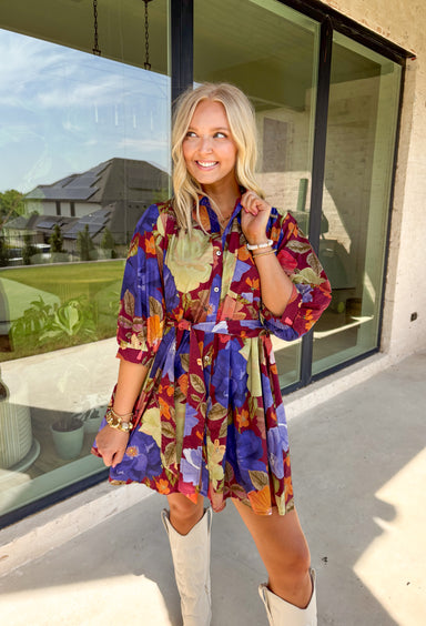 A fall favorite with effortless charm, this burgundy mini dress is blooming with autumn-inspired florals. The puff sleeves give it a feminine touch, while a front chest pocket and self-tie waist add both function and shape. Designed with a button-front closure, side pockets, and a fully lined interior, this dress is as practical as it is pretty. Made in breathable cotton, it’s an easy piece to style for everything from casual days to seasonal gatherings.