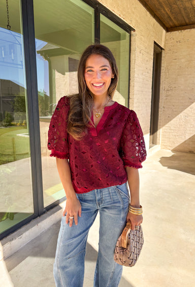 Romantic and feminine, this burgundy crochet lace overlay top by Voy is the perfect piece to elevate your fall wardrobe. The delicate lace design gives it beautiful texture, while the short sleeves and v-neckline add an effortless touch. Lettuce trim along the sleeves and hemline adds a soft, finished detail that keeps the look both classic and fresh.