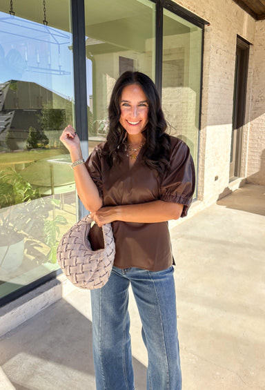 Elevate your wardrobe with this chic brown faux leather top by Entro. Designed with short puff sleeves and elasticated openings, it strikes the perfect balance of structured and feminine. The split v-neckline with a stand collar adds a modern edge, while the soft faux leather finish brings a touch of texture that feels fresh for the season. Perfect for dressing up denim or pairing with skirts, this top is a statement piece you’ll reach for again and again.
