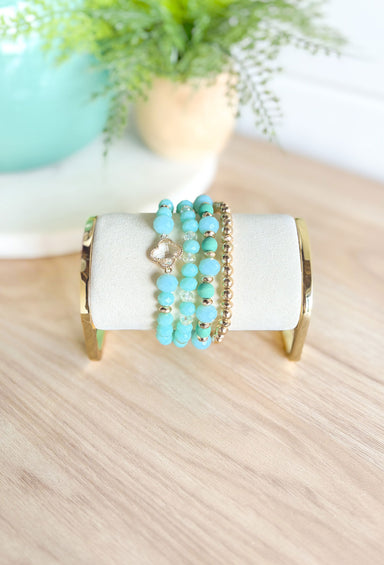 More Drama Bracelet Set in Mint, stack of 4 beaded bracelet, 3 bracelets are teal clear and gold mix, one bracelet is all gold beads