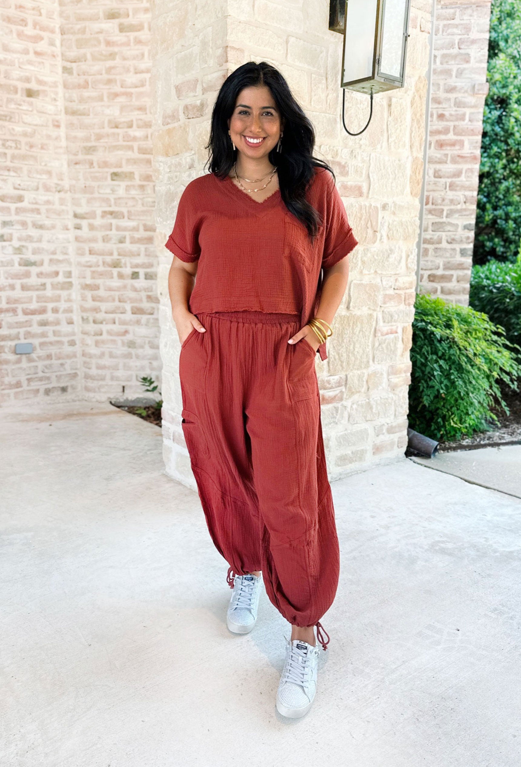Spoke Too Soon Set, Terracotta gauze short sleeve and pant set. Top has a textured hem along with a front pocket and soft v-neck line. Pants are a jogger/cargo style with drawstrings on the ankles and multiple pockets.