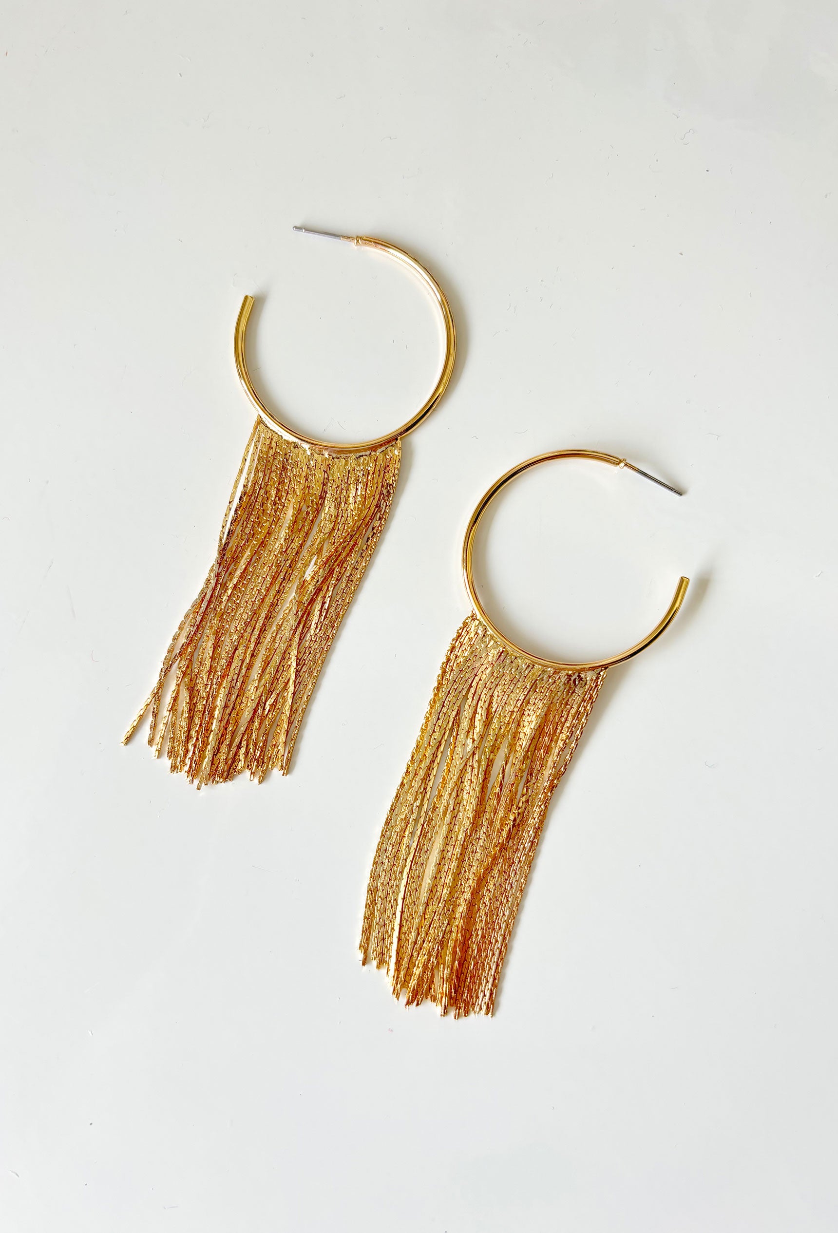 A Little Drama Earrings, gold hoop with gold fringe on the bottom of the hoop 