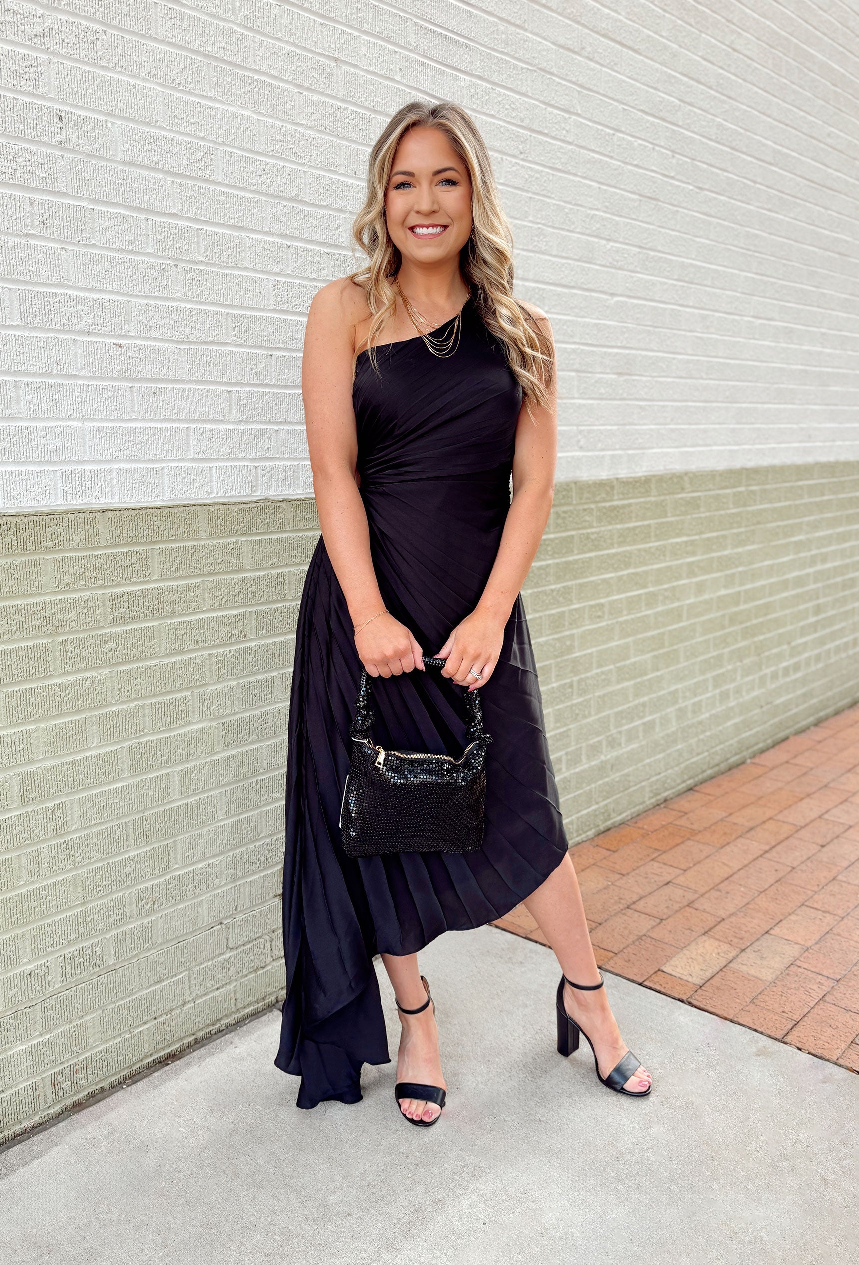 All Time Classic Dress, one shoulder pleated black dress with asymmetrical bottom and open circle on the right side of the dress 