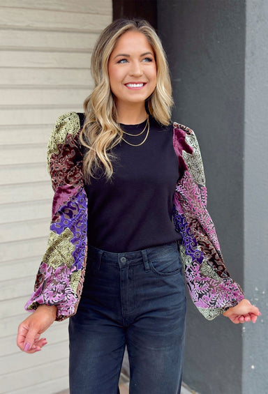Nothing But The Best Top, black top with abstract shaped velvet sleeves with colors indigo, violet, green, burgundy, and orchid