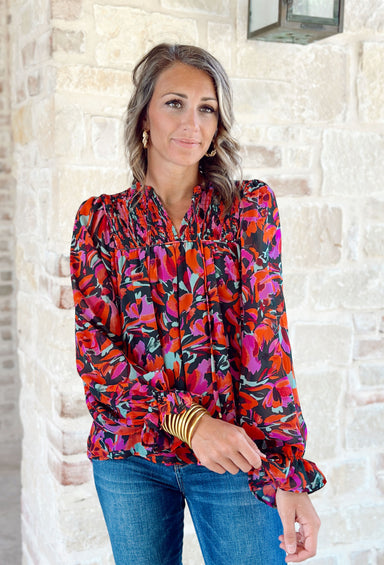 One Last Kiss Blouse, long sleeve blouse with red and purple floral print, green leaves, and a black background. Wrists are cinched with ruffles on the end and small portion of the shoulders are cinched 