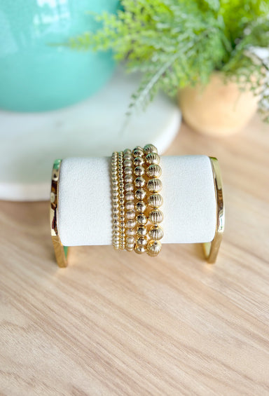 Return To You Bracelet Set, stack of five gold beaded bracelets, varying in size, three are textured two are smooth 