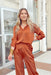 Stay With Me Set, satin button up top with satin wide leg pants that have an elastic waist band, both pieces are a rust color