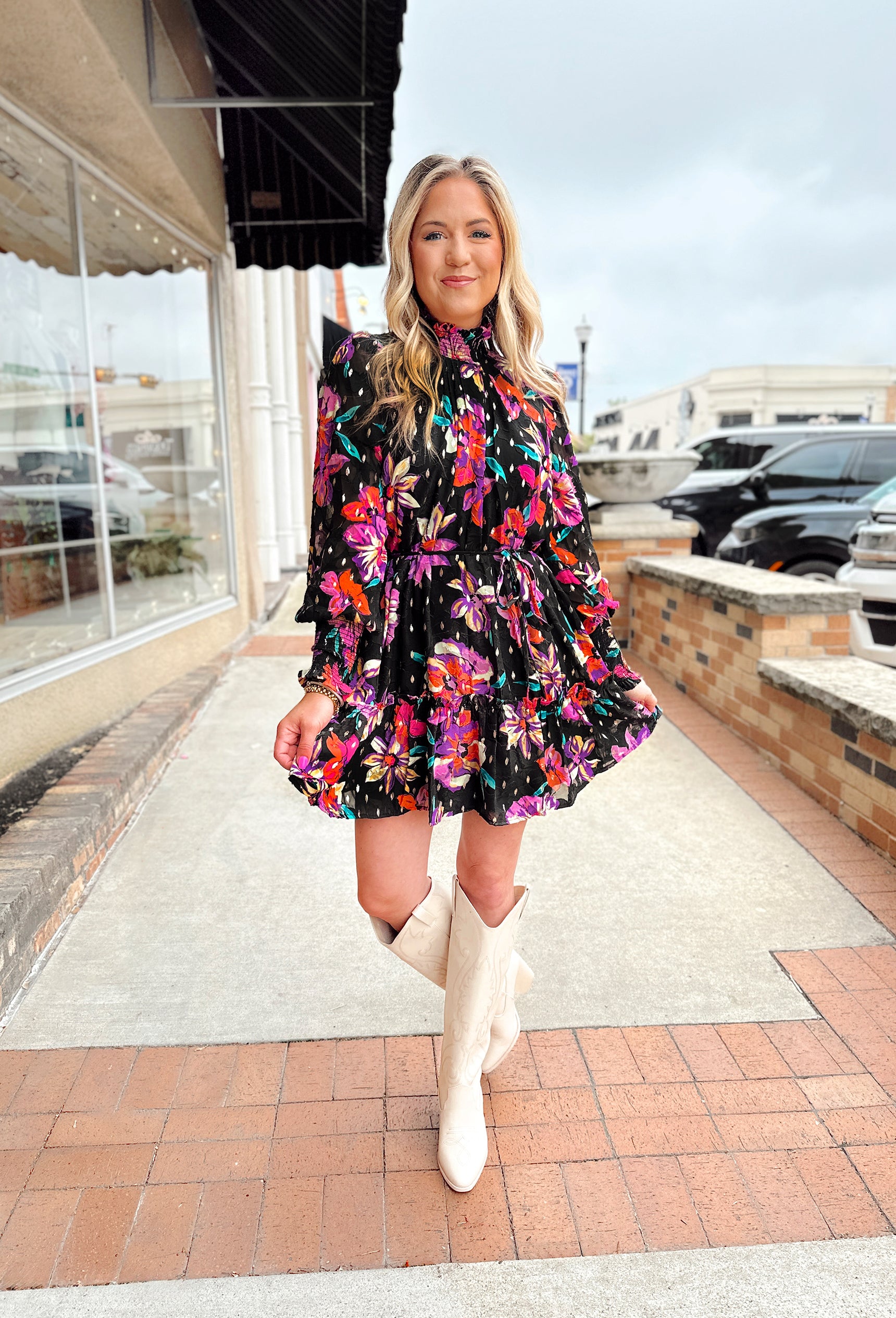 Sweetest Wish Floral Dress, black longsleeve dress with high neck that has cinching and ruffle hem along with cinched wrists with ruffle hem. 2 tiers and red, gold, purple, and green floral pattern