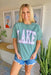 Charlie Southern: Lake Graphic Tee, green comfort color tee, "lake" written on front with white lettering and pink outline