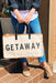 The Getaway Canvas Tote, cream canvas tote with 'getaway' written in black block letter and tan leather trimming 