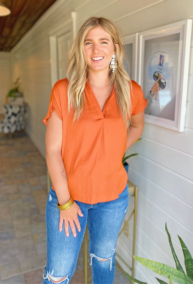 Kerry Blouse in Pumpkin, orange short sleeve blouse, satin material, pleated detail at the bottom of the v-neck
