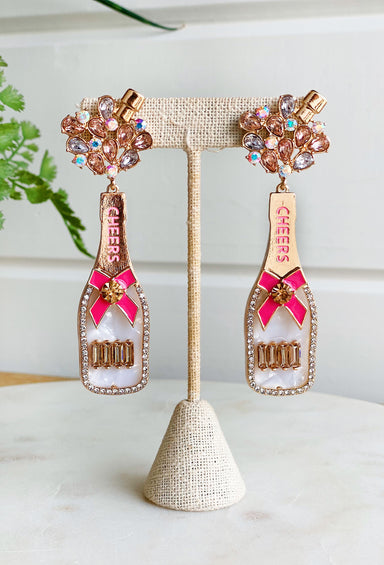 Pop The Champagne Earrings, hard acrylic earrings int he shape of a champagne bottle, pave crystals and pink cheers written at top
